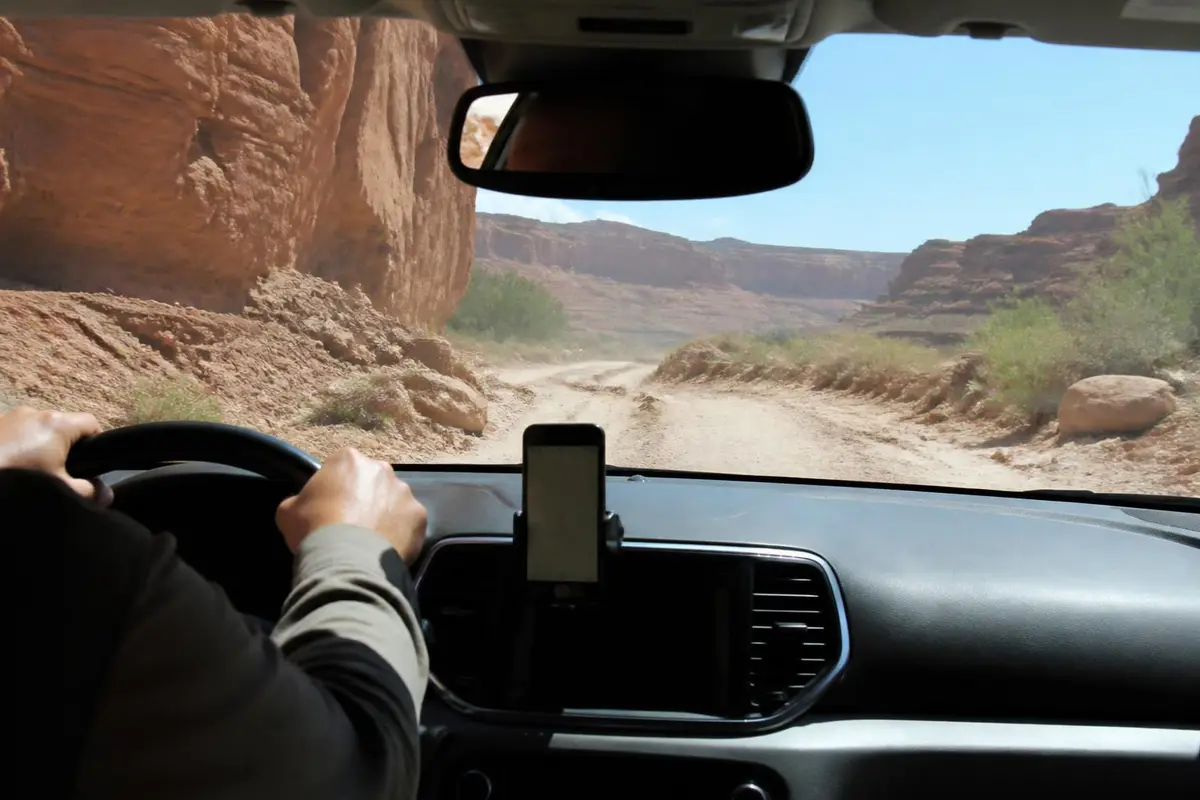 Hands on the wheel of a pickup on a rutted desert track