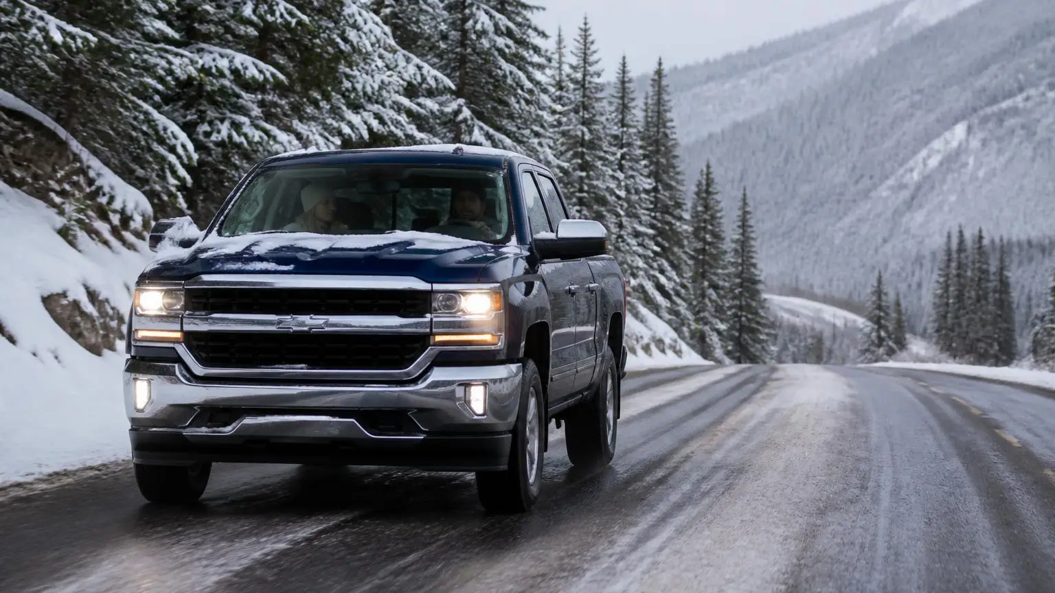 Full-size pickup driving a snowy mountain road