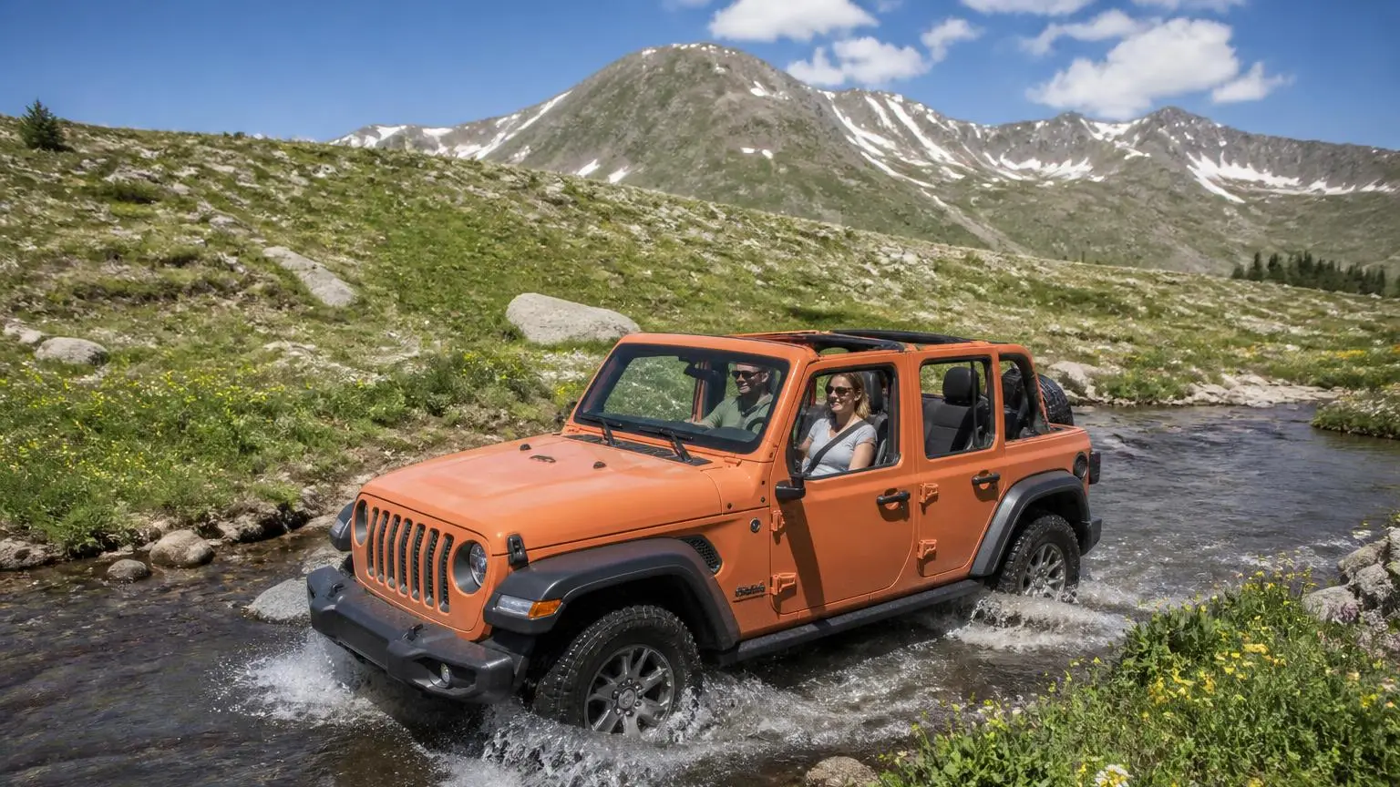 Four-door off-roader with roof off crossing a mountain stream