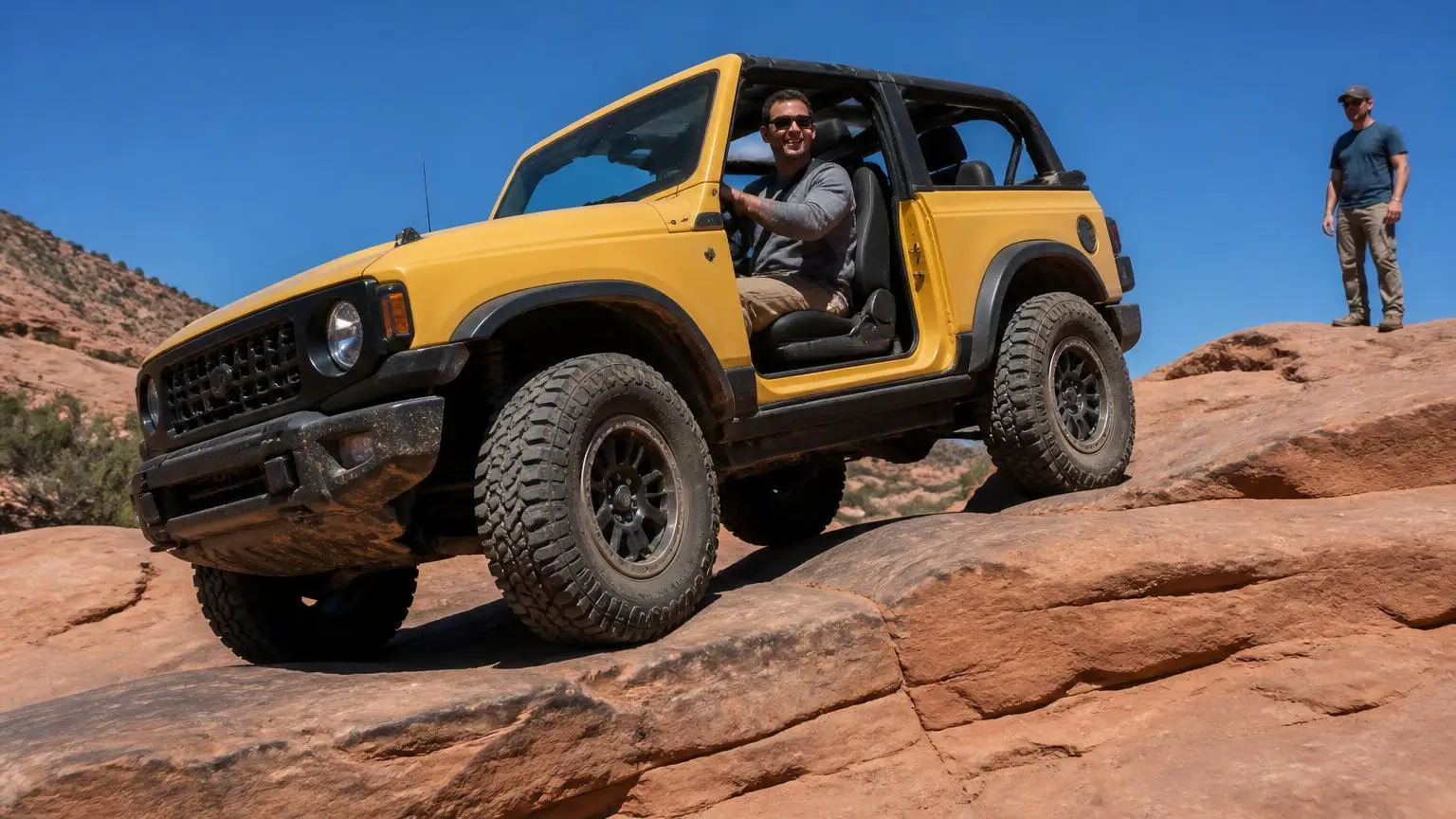 Two-door off-roader crawling over red slickrock