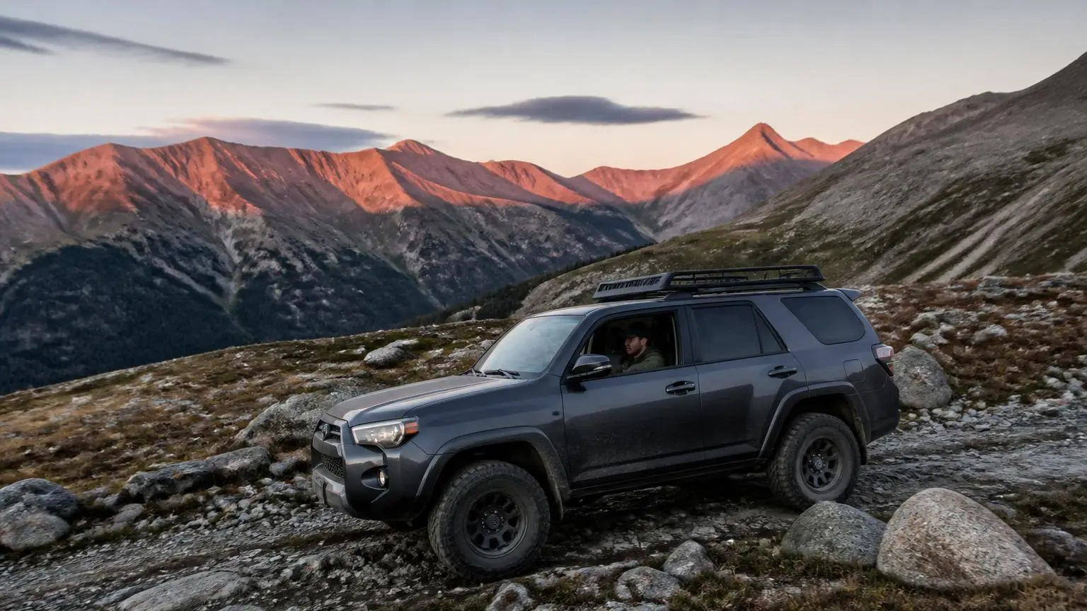 Mid-size SUV climbing a rocky mountain trail at dawn