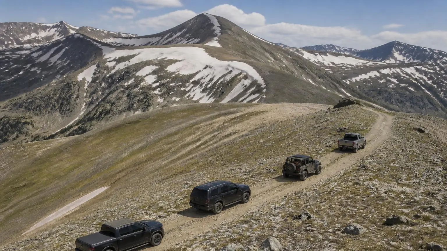 Several different 4WDs driving in convoy on a mountain trail