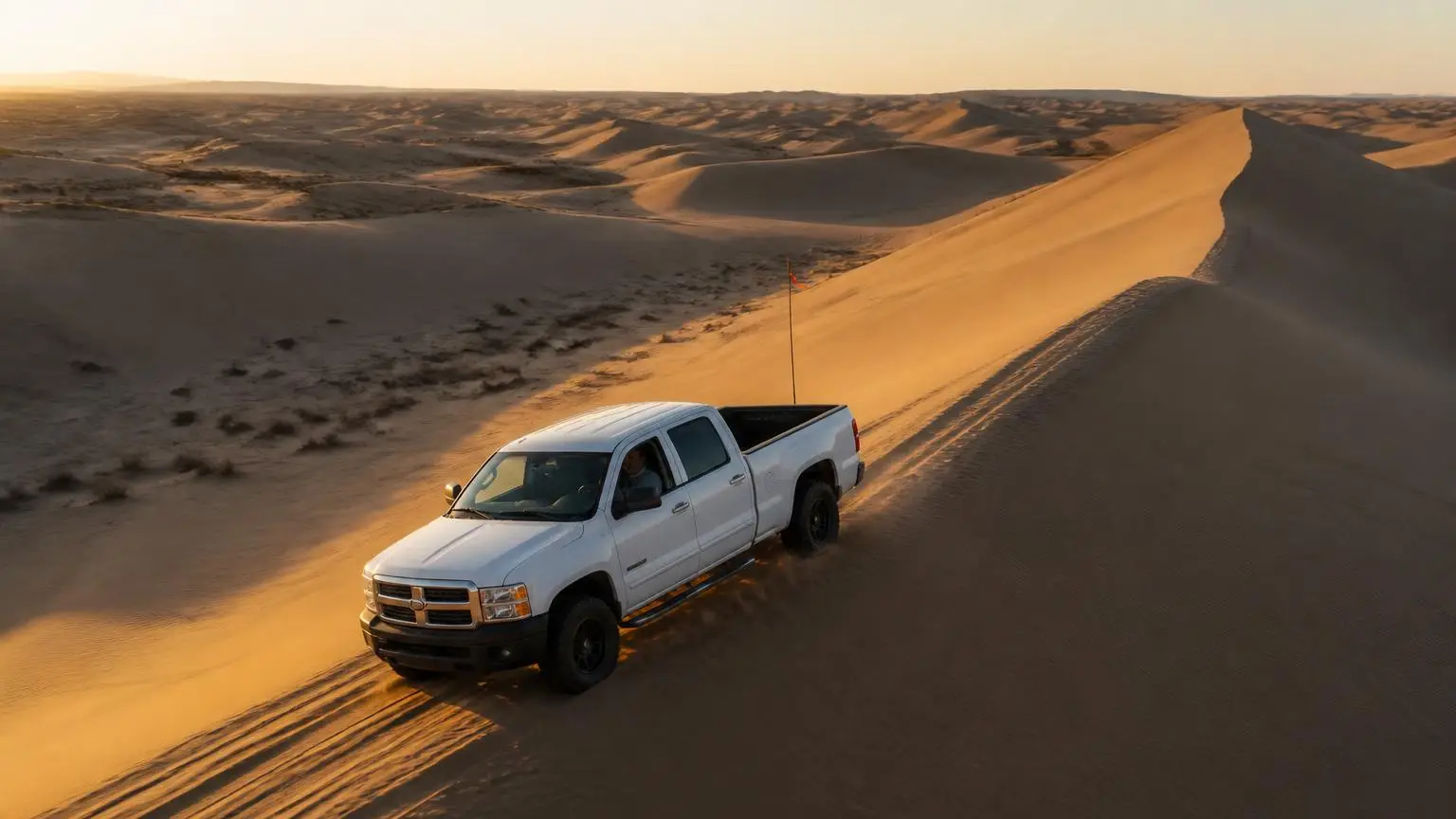 Illustrative: full-size pickup with aired-down tires in towering desert dunes