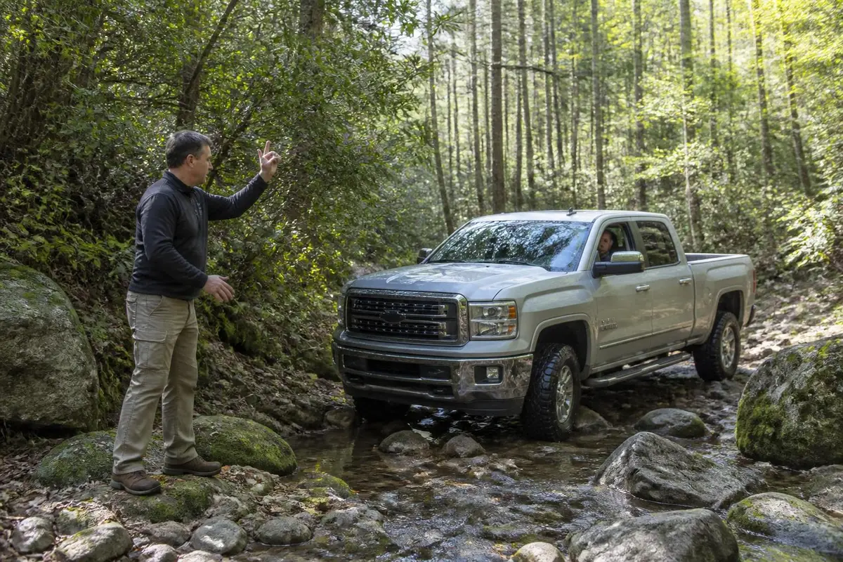 Illustrative: spotter guiding a rig through a rocky creek bed