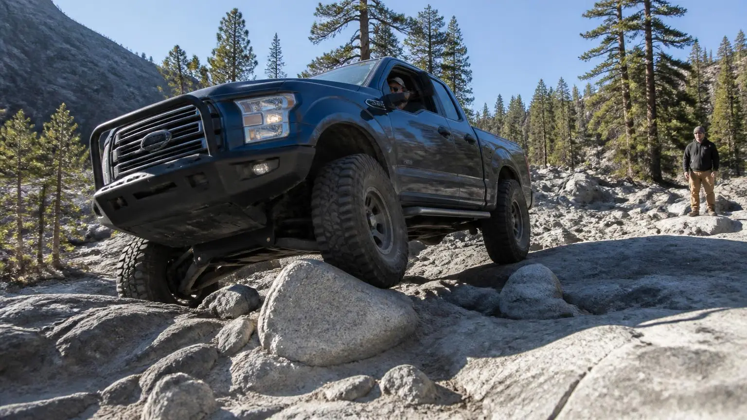 Armored 4WD crawling over boulders with sliders taking the weight