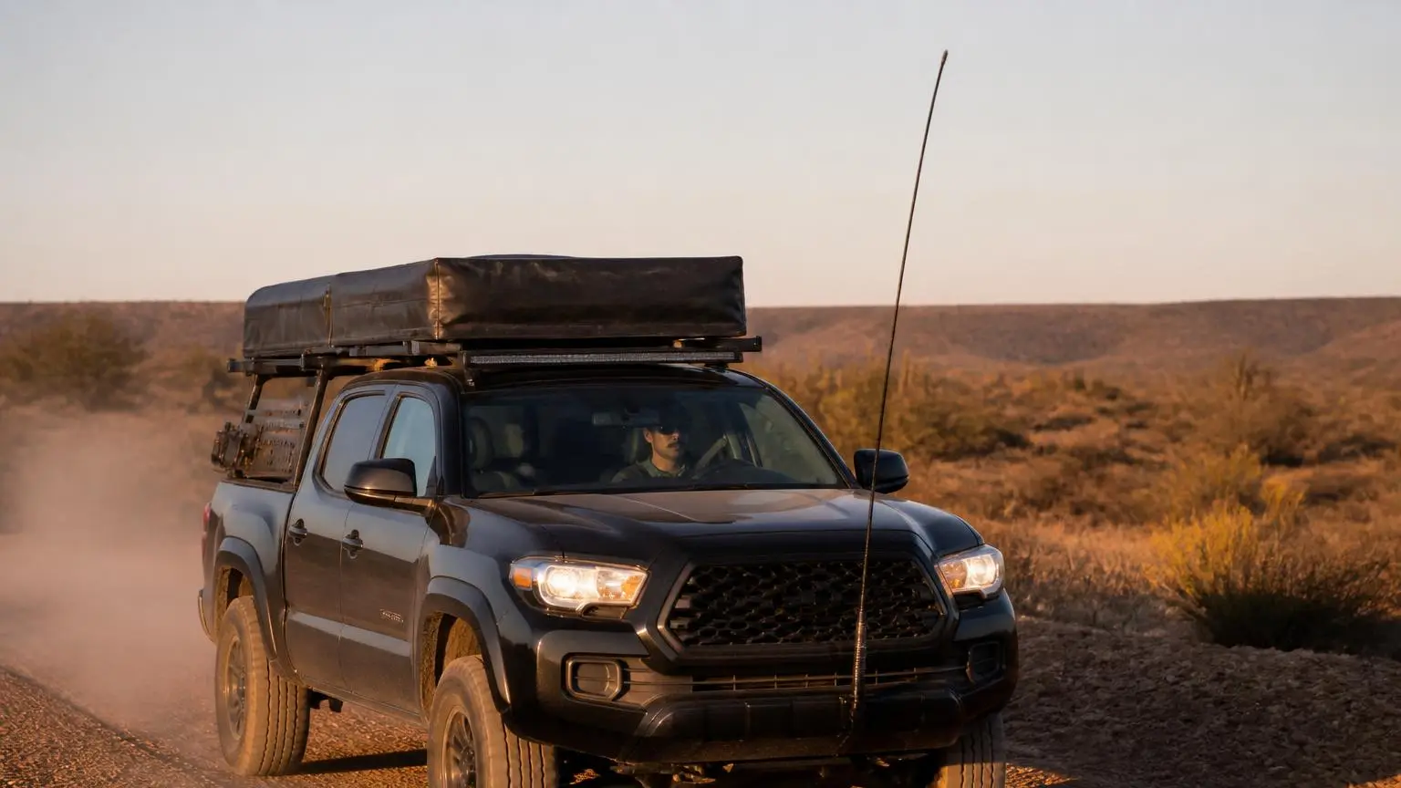 Pickup with a tall whip antenna on a dusty desert road