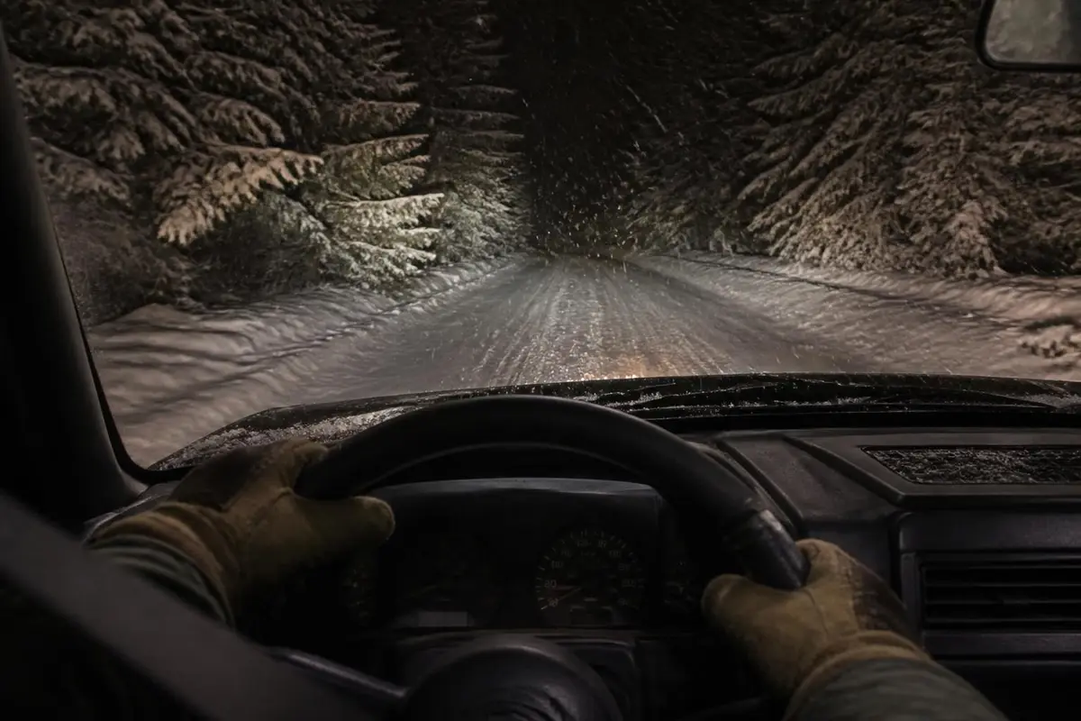 Dashboard view out the windshield with warm auxiliary lights on a snowy road