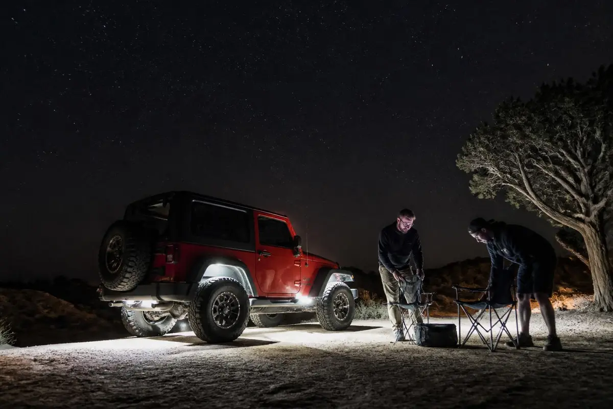 Camp at night lit by soft rock lights under an off-roader