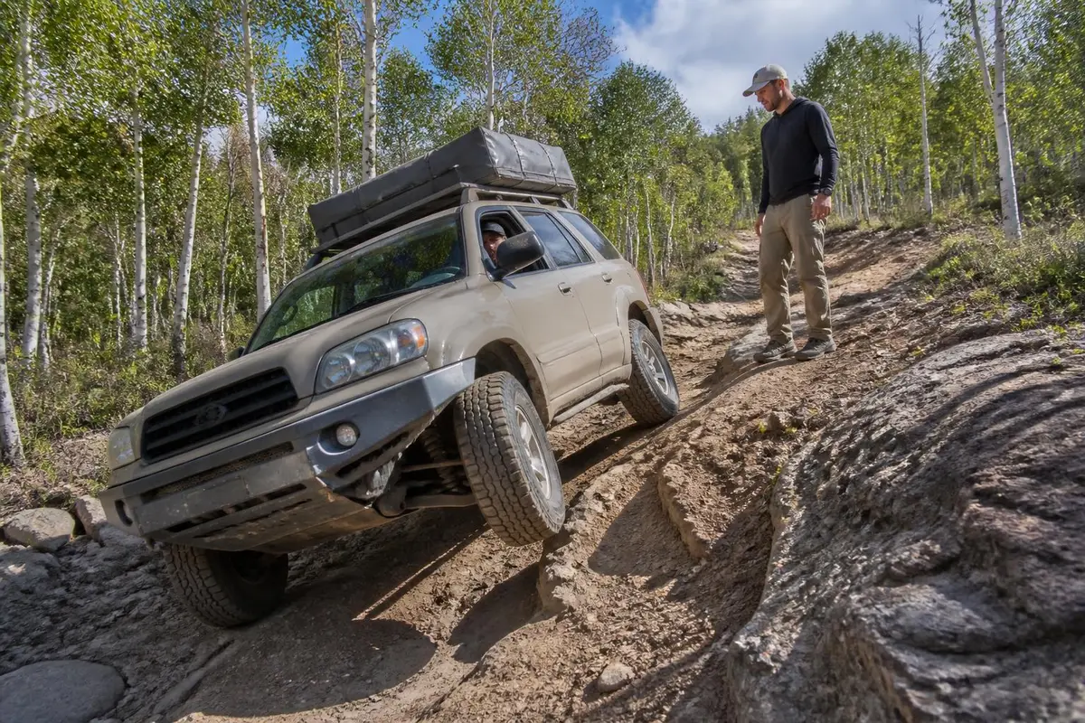 Tall-loaded SUV leaning on an off-camber trail