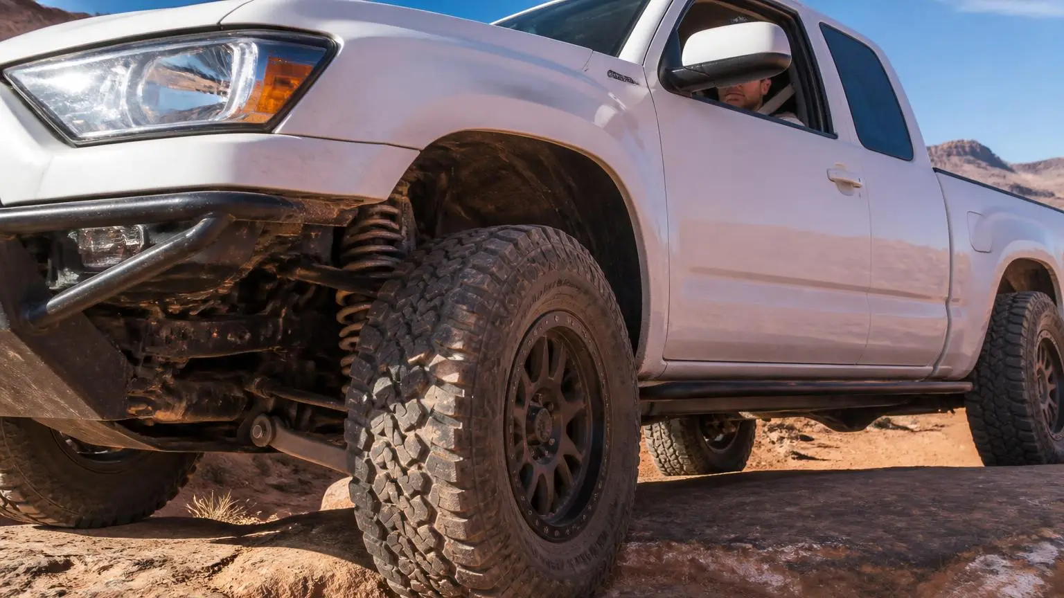 Lifted independent-front-suspension pickup crossing a rock step