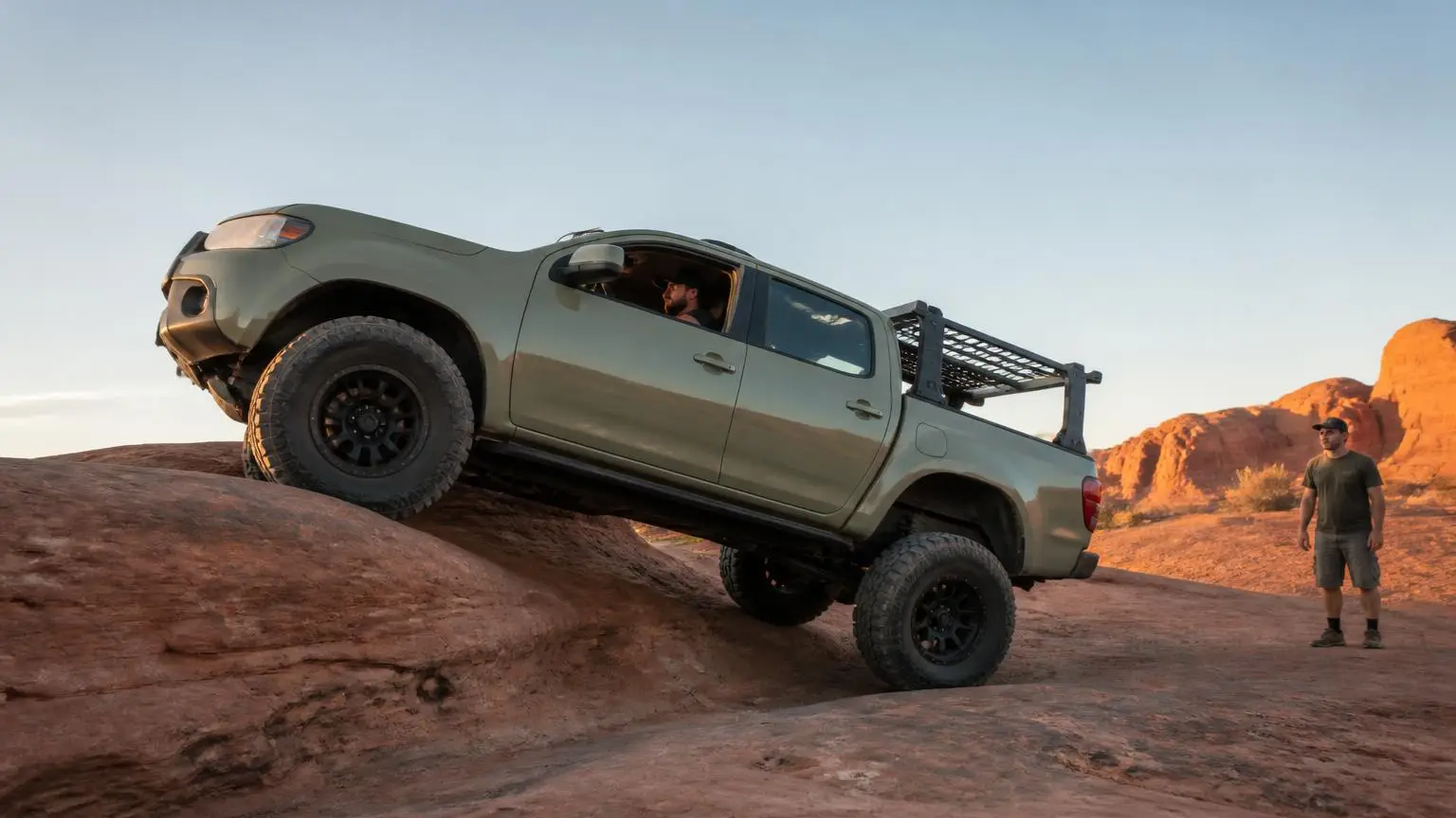Lifted pickup on oversized tires crawling a sandstone ledge