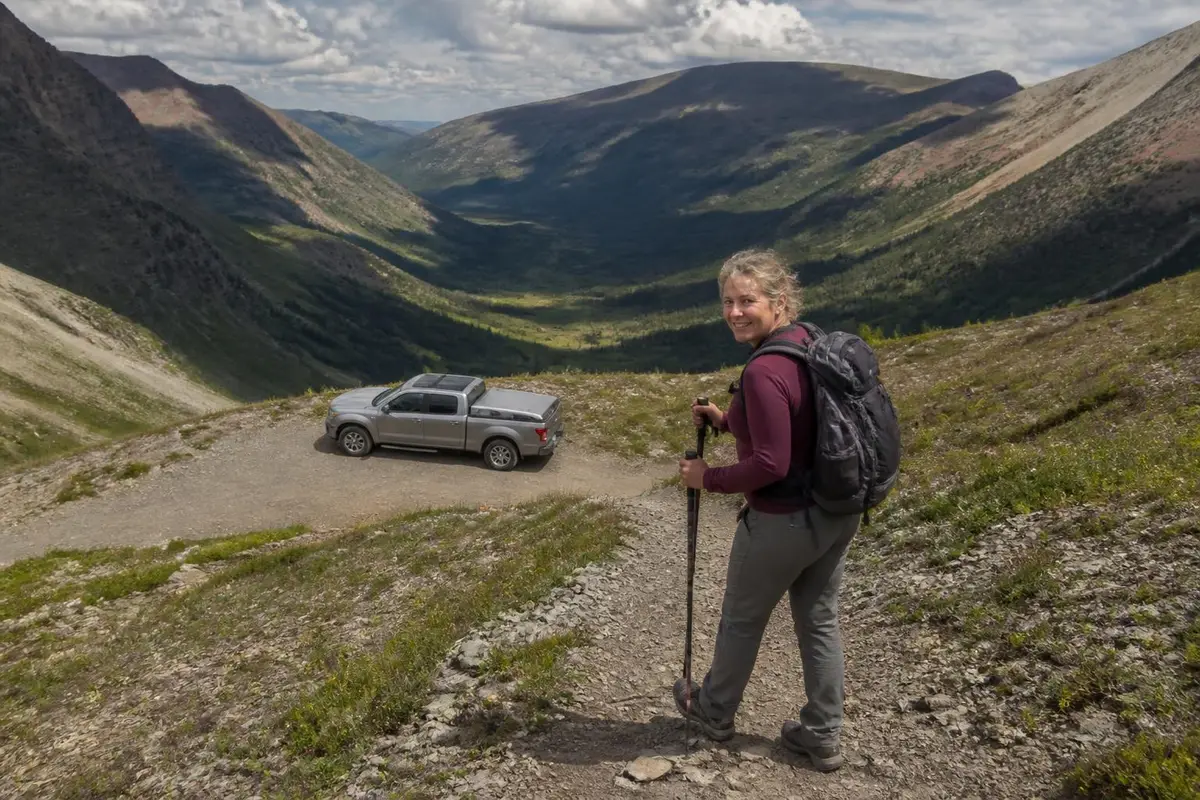 Hiker returning to a pickup with a closed cover at a remote trailhead