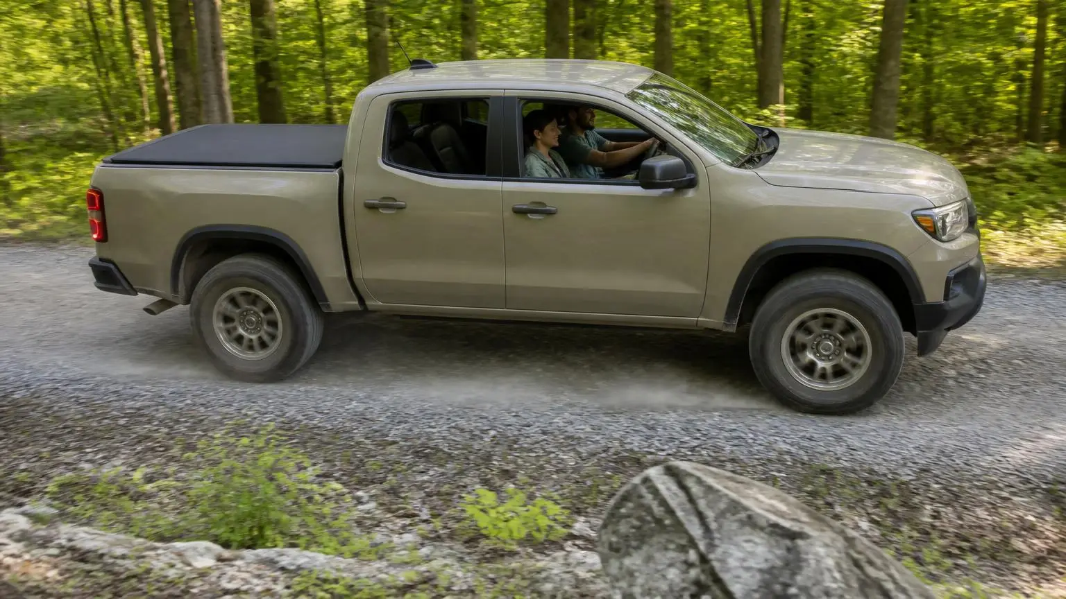 Pickup with a soft roll-up cover on a gravel forest road