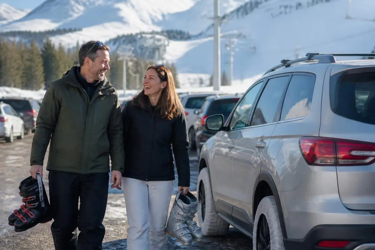 Couple walking to their SUV in a snowy ski resort parking lot