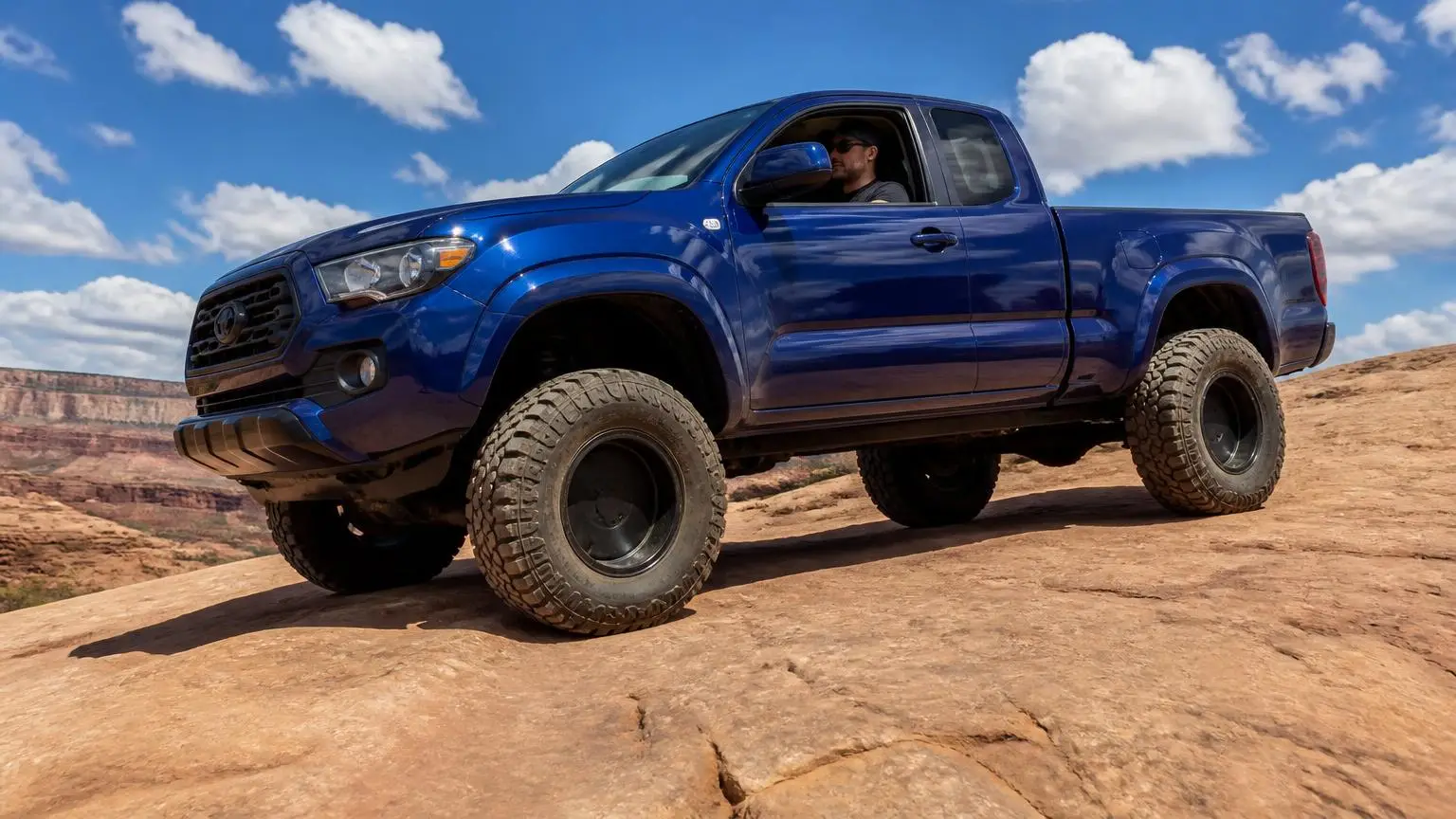 Lifted pickup on all-terrain tires crossing slickrock
