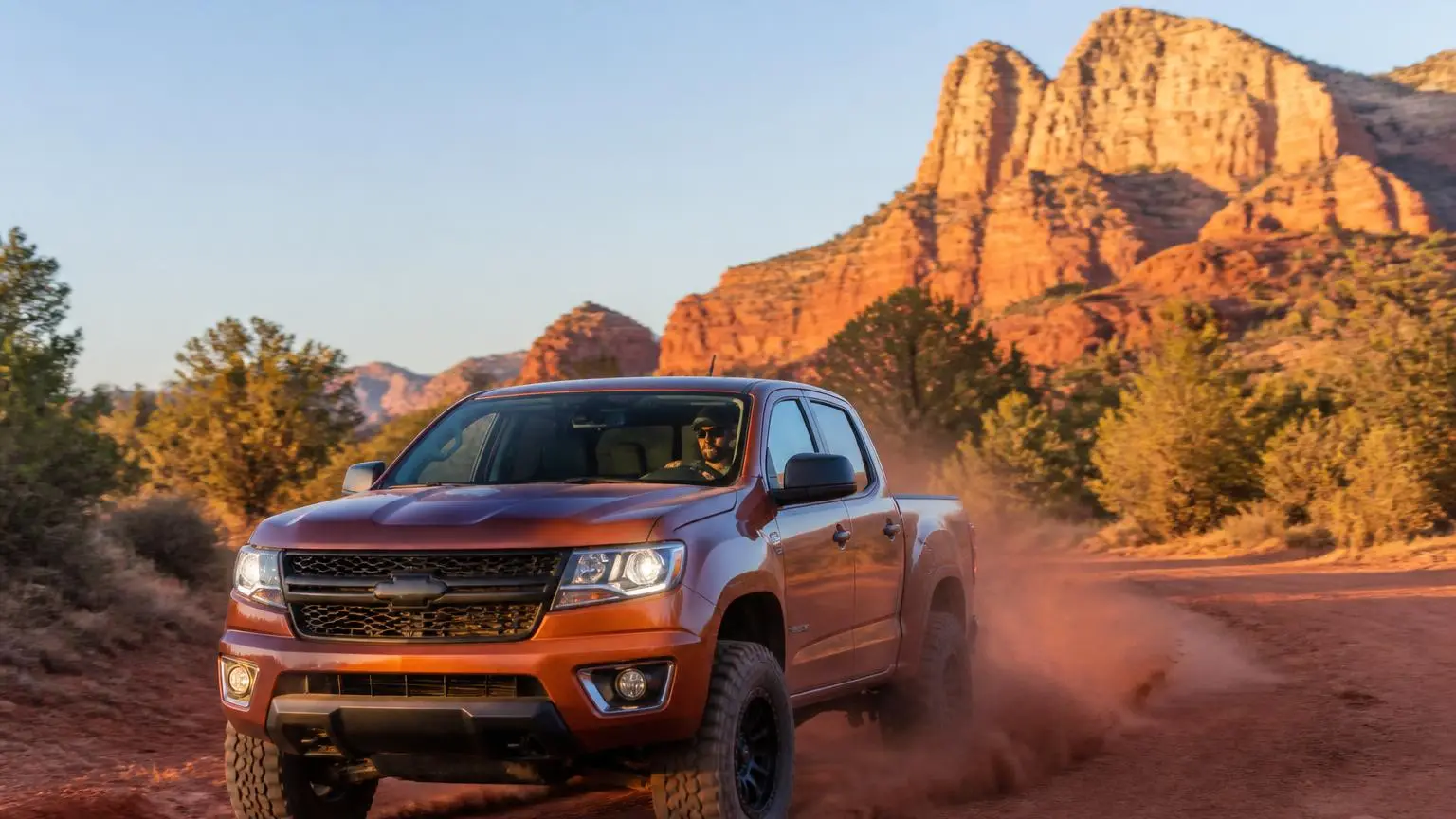 Pickup on all-terrain tires crossing a red dirt desert road