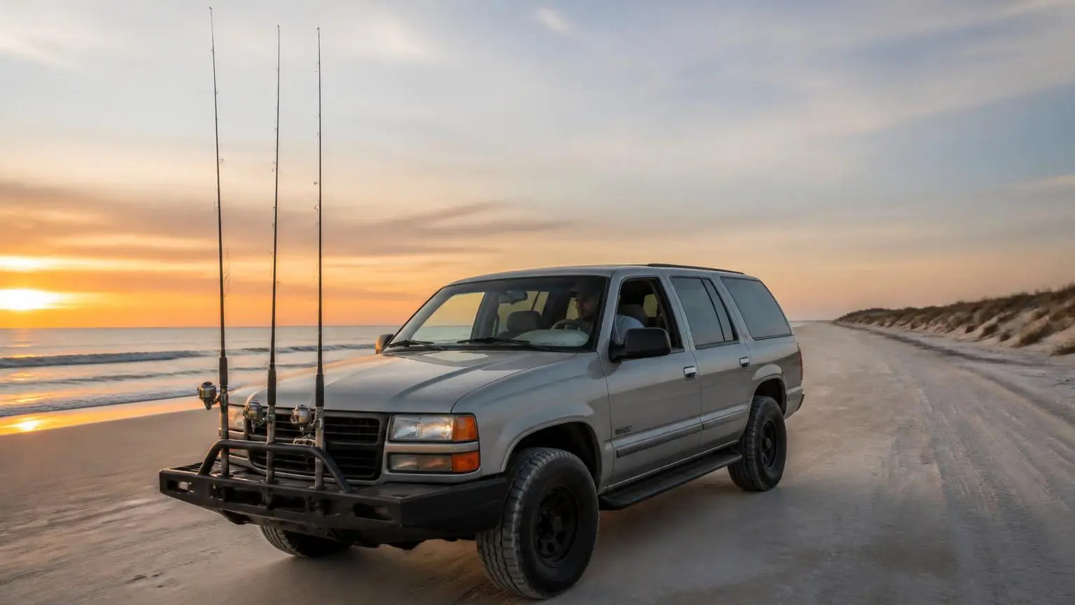 Aired-down SUV driving along a wide sandy beach