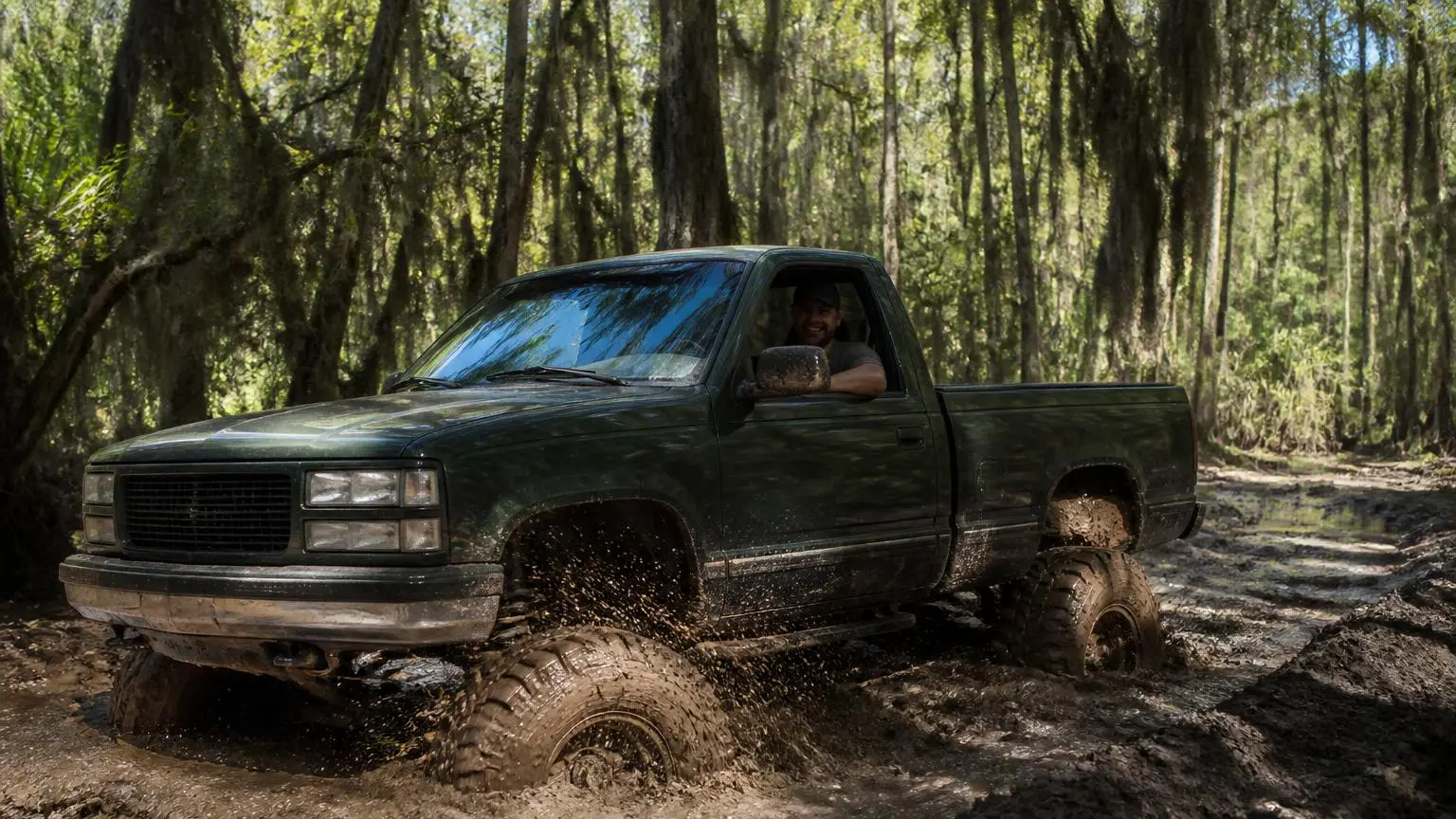 Pickup on mud-terrain tires slogging through a bayou mud track