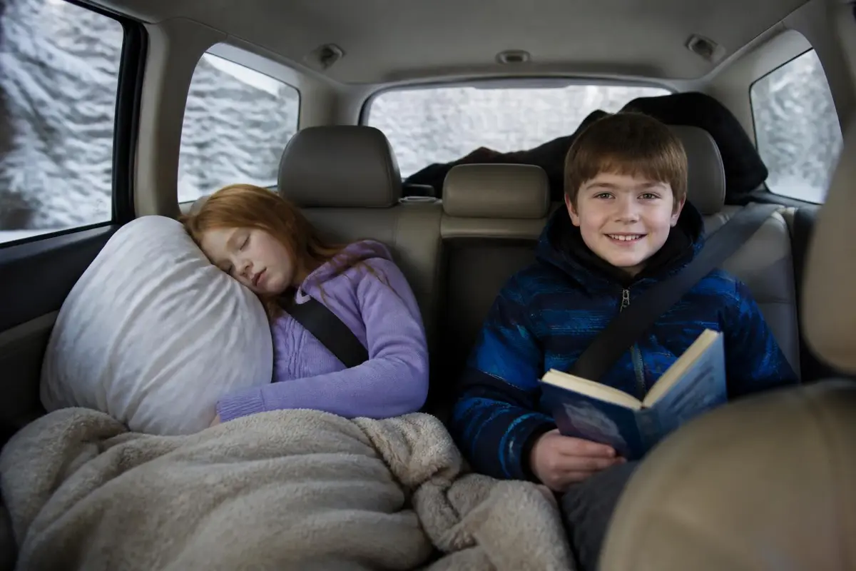 Kids in the back seat of an SUV on a winter road trip