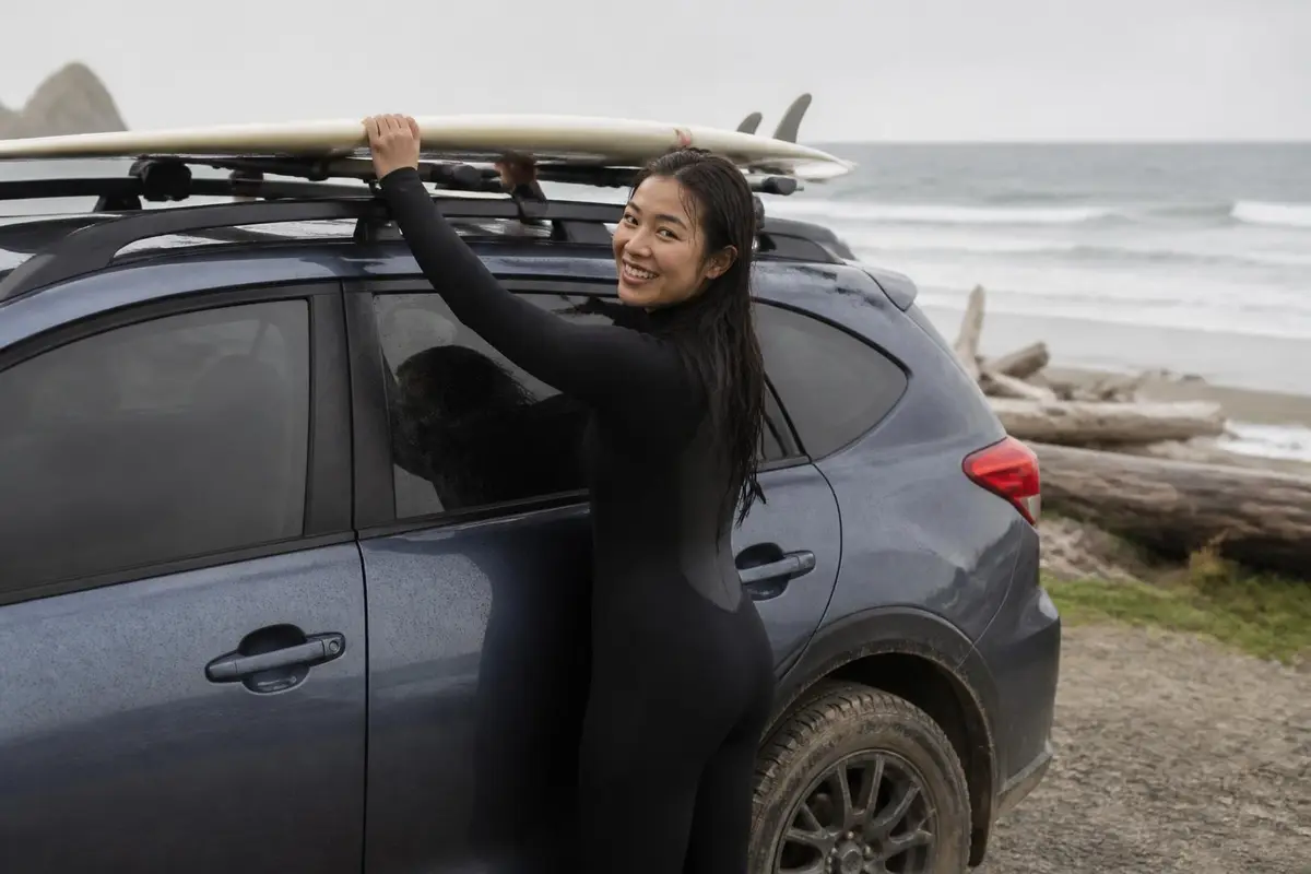 Young woman loading surf gear onto a crossover roof