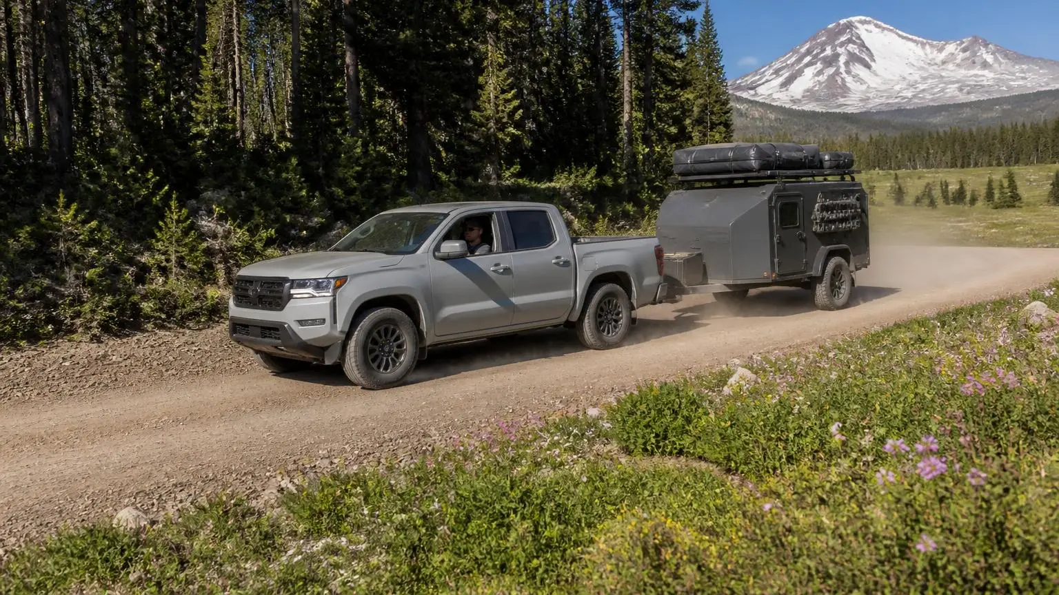 Pickup towing a small overland trailer on a forest road