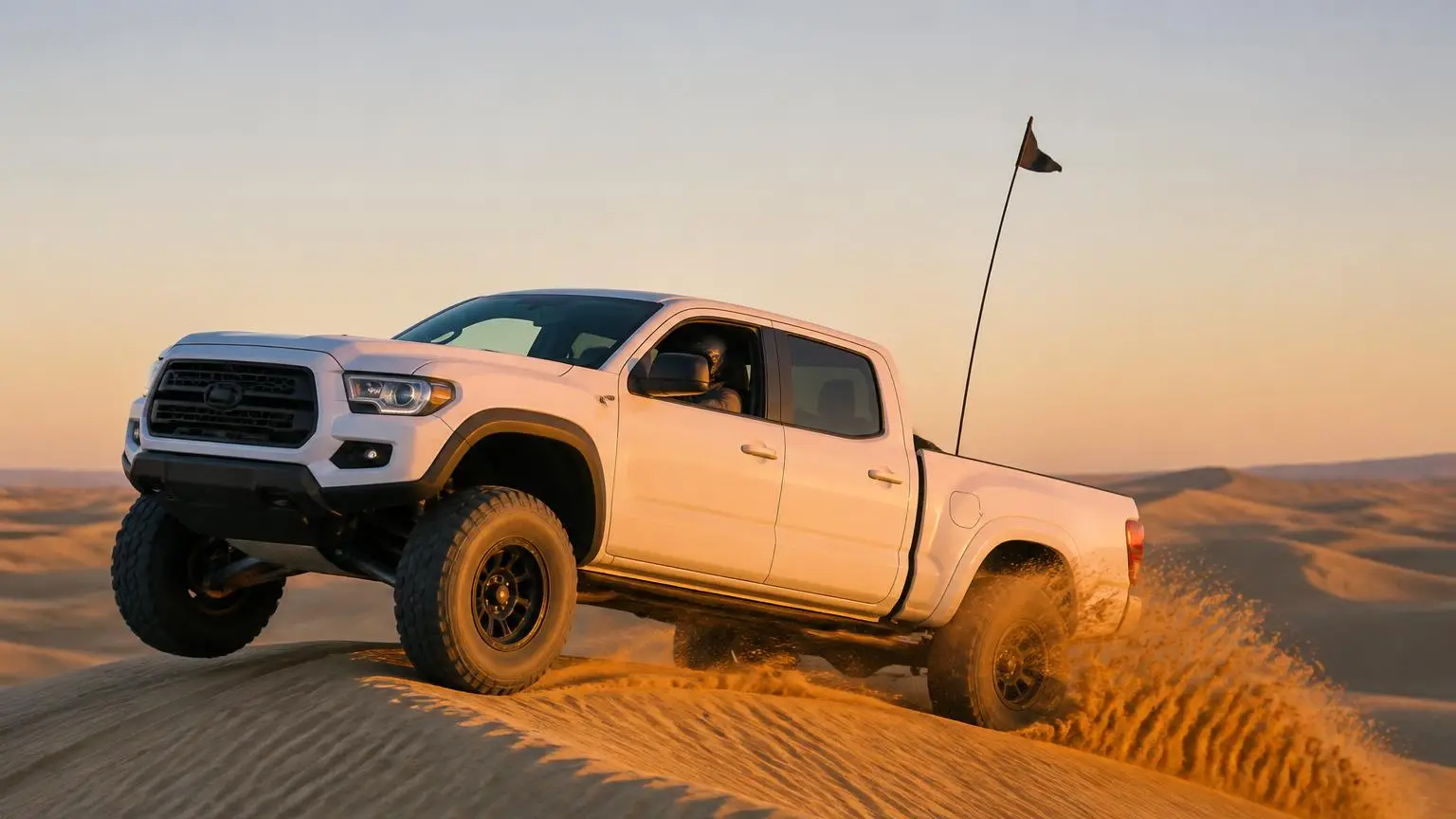 Long-travel pickup crossing sand dunes with aired-down tires