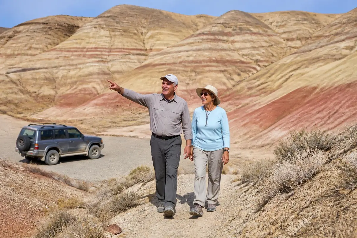 Couple walking a badlands trail near their parked off-roader