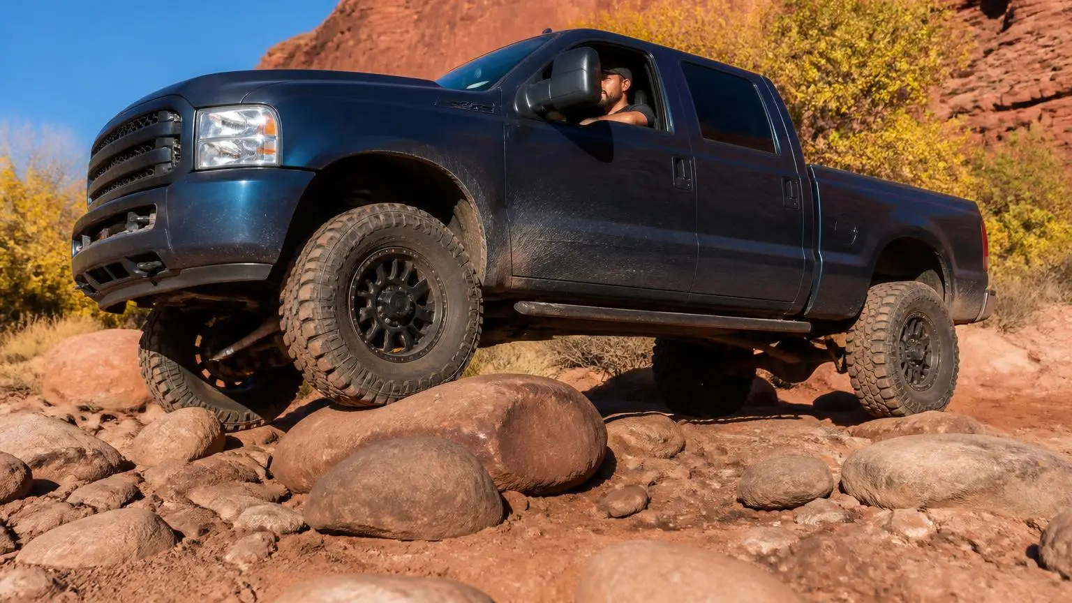 Heavy-duty pickup on all-terrain tires crossing a rocky wash