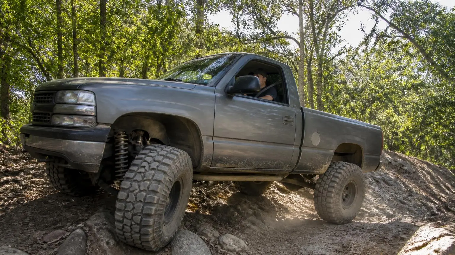 Lifted pickup on huge mud-terrain tires climbing a rocky hill
