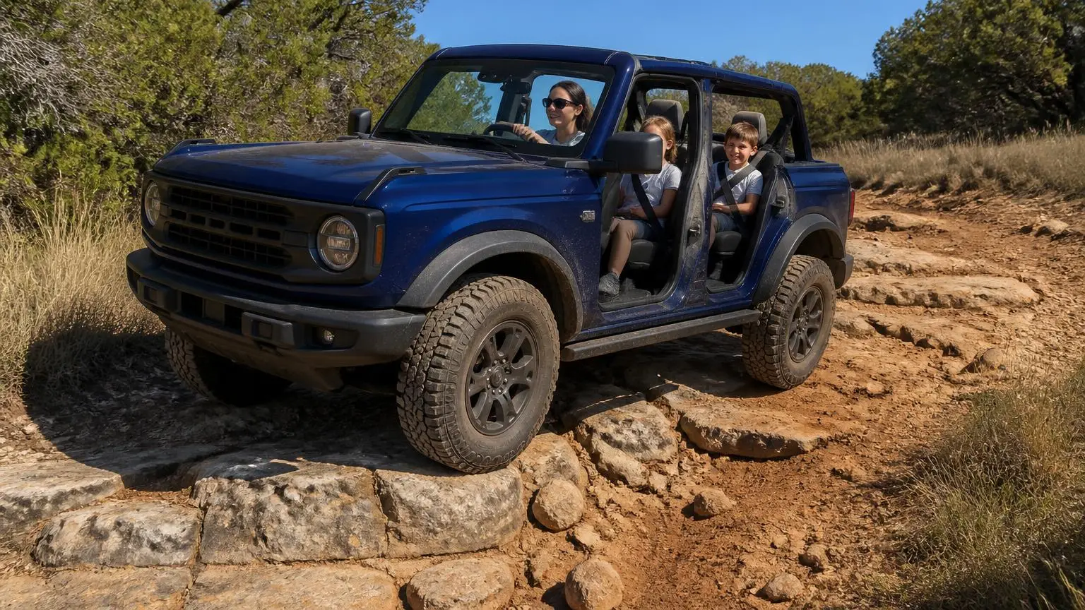 Dark blue four-door off-roader with roof panels off crawling over mixed rock and dirt
